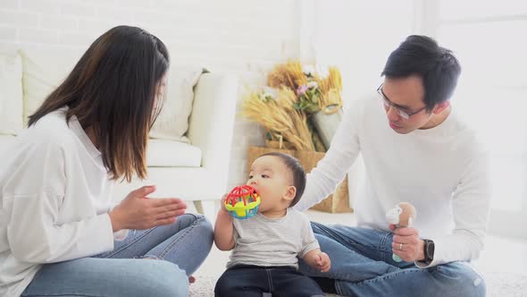 Asian Family of Father and Mother Playing Toy Doll with Their Son on Sitting on the Floor at Home