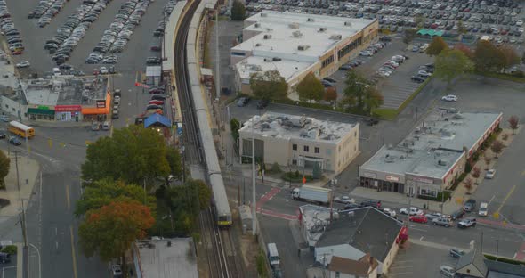 Backwards Aerial Pan Following Shot of a Train Passing Through a Small Town