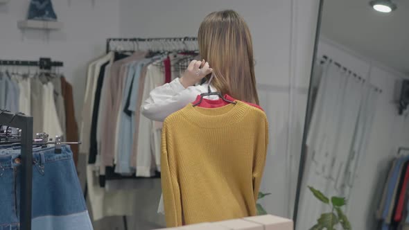 Slim Confident Woman Hanging Sweaters on Shoulder Turning Looking Back