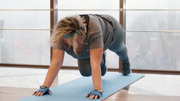 Overweight Woman Doing Exercise on Mat in a Gym