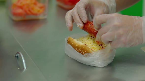 CU Slow Motion Cook Prepares a Hot Dog Puts the Fried Sausage Into It