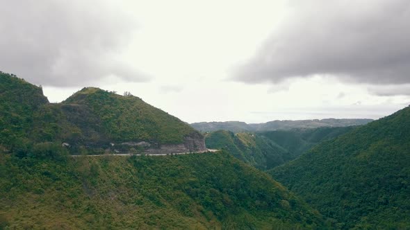 Aerial rising up and slowly panning across a huge valley covered in lush green forest in central Ceb