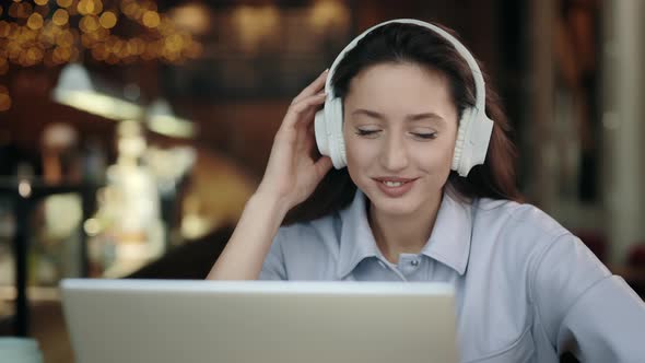 Woman at Cafe with Laptop Listening Music in Headphones