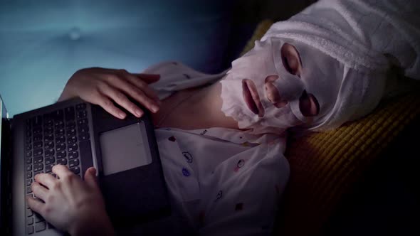 Portrait, Woman in Cosmetic Fabric Mask and White Towel on Her Head, Fell Asleep in Front of Laptop