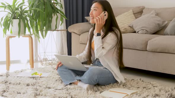 Smiling Asian American woman talking on phone, making or answering call, having pleasant conversatio