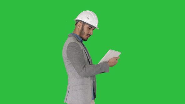 Engineer walking and working on digital tablet on a Green