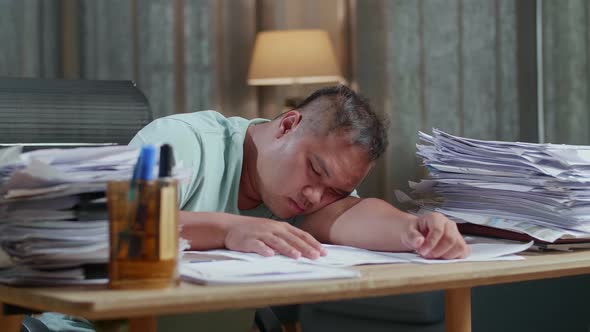 Close Up Of Fat Asian Man Sleeping Due To Working Hard With Documents At The Office