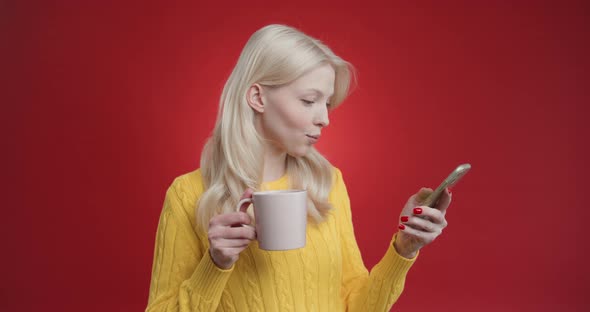 Young Woman Drinks Cup Tea and Uses Phone Reads News Looks at Camera in Surprise Show Green Screen