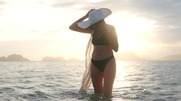 Woman In Bikini And Sun Hat Smiling In Sea At Sunset