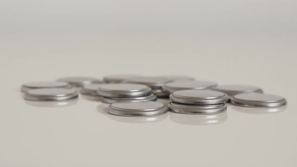 Metallic button watch batteries on white 4K tilting footage