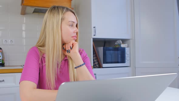 Freelancer woman in thought looking away in front of laptop computer
