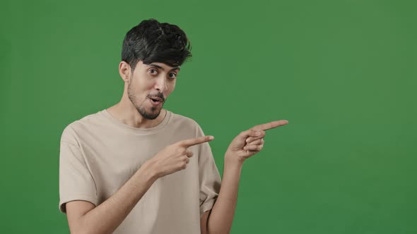 Optimistic Humorous Portrait Arabic Man Posing in Green Studio Points Forefingers Aside Pretending