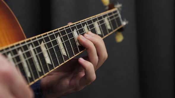 Human fingers playing on guitar close up view of fretboard and strings