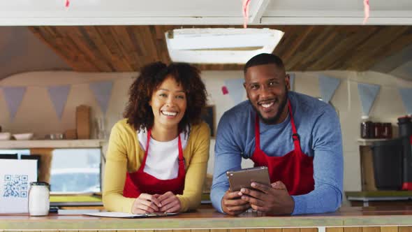 Portrait of african american couple wearing aprons smiling in food truck