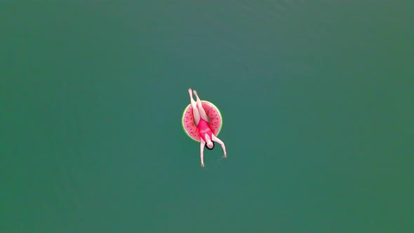 Overhead Top View of Woman Swimming with Watermelon Swimming Circle in Blue Water