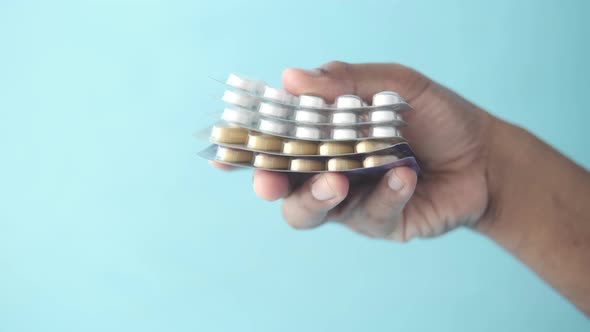 Hand Hold Pills of Blister Pack Against Blue Background