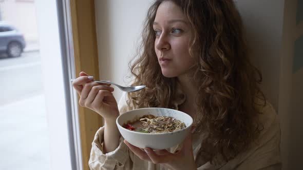 Woman Eats Sweet Vegan Cereal Bowl Sitting on Windowsill