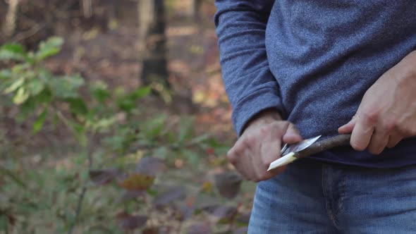 A man slicing a branch with a knife