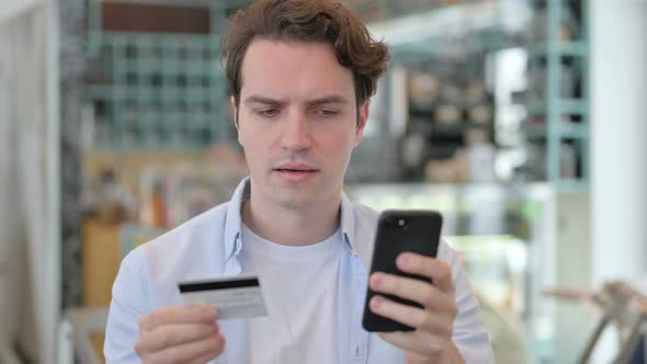 Portrait of Young Man with Successful Online Payment on Smartphone