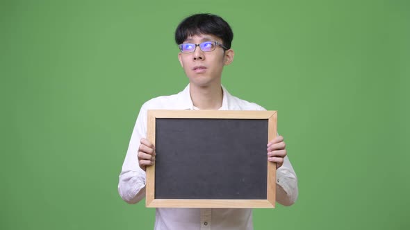 Young Asian Businessman Holding Blackboard While Thinking