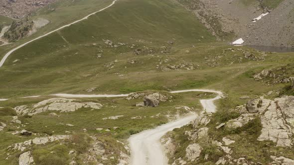 Cinematic Aerial View Gravel Trail Road on the Mountain. Cloudy Weater, Mist and Haze. Forward Dolly