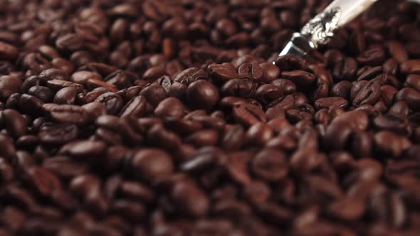 Stir roasted coffee beans with a metal spoon.