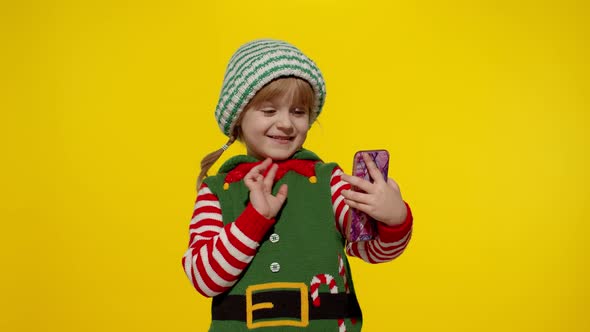 Kid Child Girl in Christmas Elf Santa Claus Helper Costume Making a Video Call on Mobile Phone