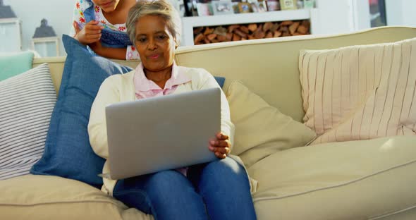 Grandmother and granddaughter using laptop in living room 4k