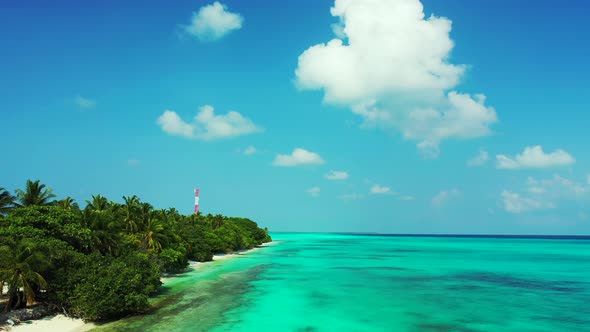 Bright blue sky with static white clouds hanging over turquoise lagoon washing shore of tropical isl