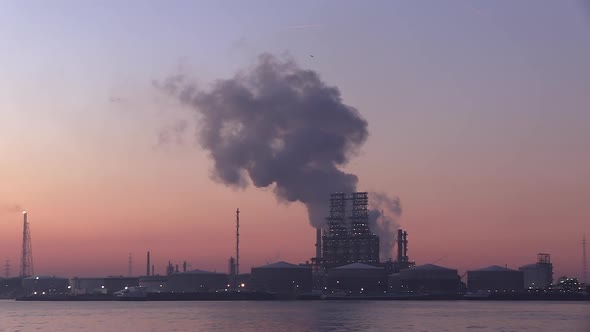 a huge steamy cloud rising from a petroleum refinery at the port of Antwerp at dawn