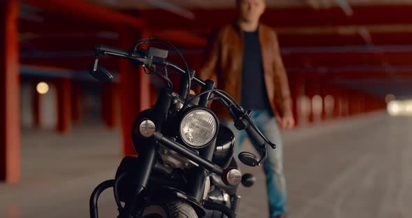 Young Man Approaches a Motorcycle and Sits on It