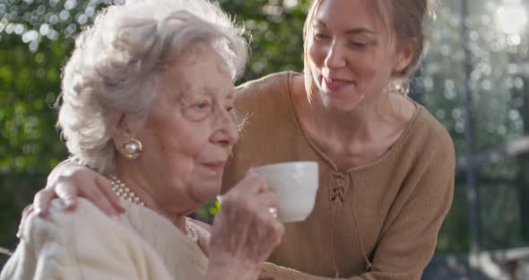 Granddaughter Visitinghappy Hugging Grandmother at Outside Gardenbacklight Sun