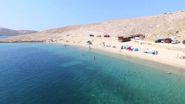 Flying above tourists on isolated beach of Pag island, Croatia