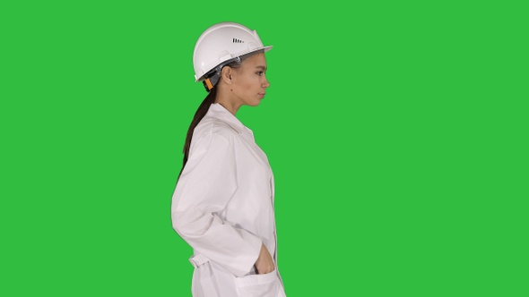 Woman in white robe putting hard hat on while walking on