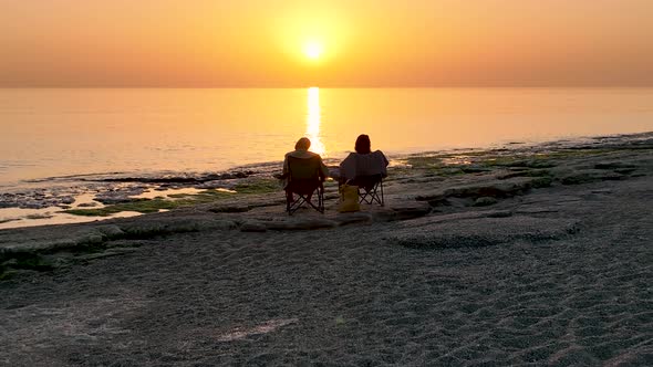 People sit on the beach and watch the sunset