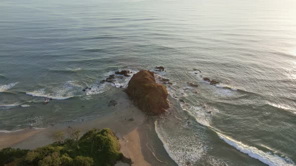 Drone orbiting around a big rock on the tip of a tropical peninsula that reaches out into the pacifi