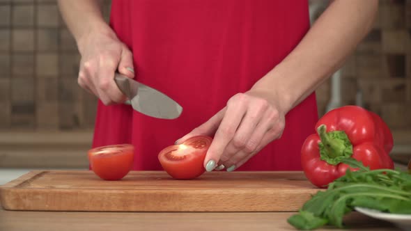 Woman Cuts Tomatoes in the Kitchen on a Cutting Board Closeup