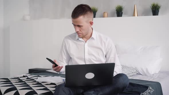 Young Man Using Laptop and Cellular Phone