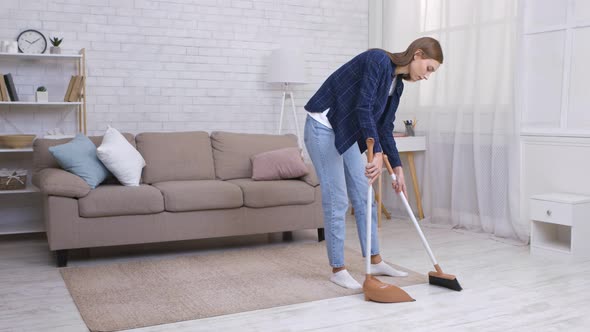 Young Woman Sweeping Floor at Home Using Broom and Scoop Slow Motion