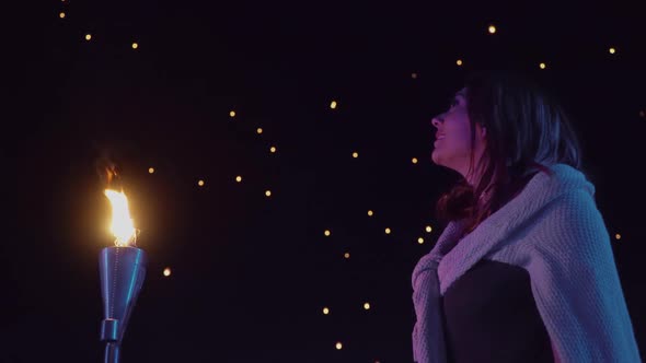 Woman watches as sky lanterns fly Into the night sky