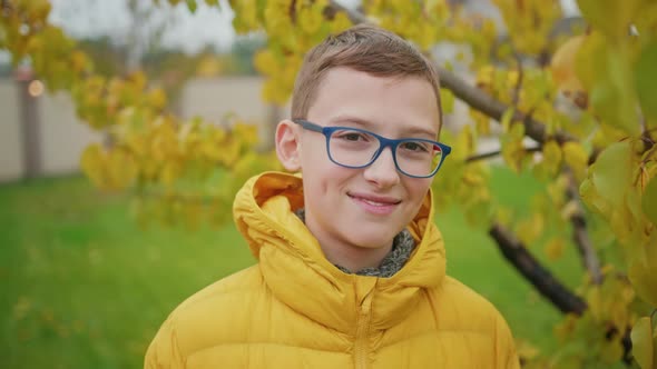 Close Up Smiling Boy in Reading Glasses Outdoors Yellow Foliage on Autumn Back