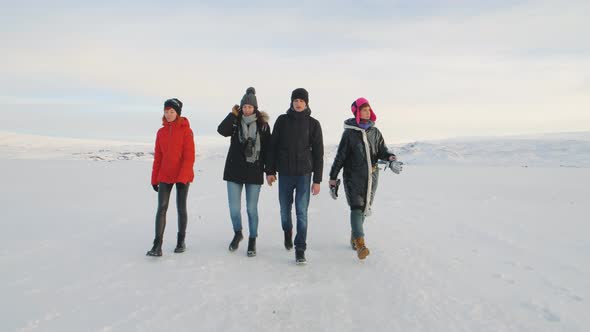 Four Traveler Friends Walking on a Snow Desert in Iceland at Sunrise