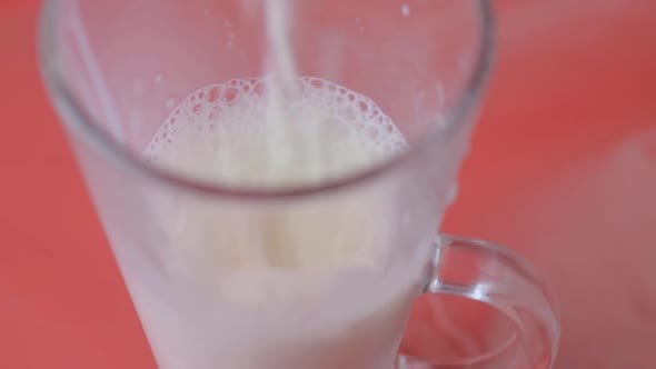 Pouring milk into a glass on a red background