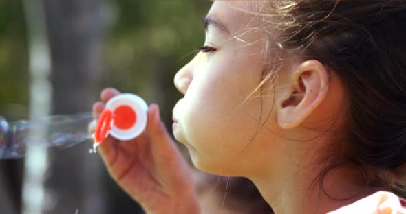 Close-up of schoolgirl playing with bubble wand in playground