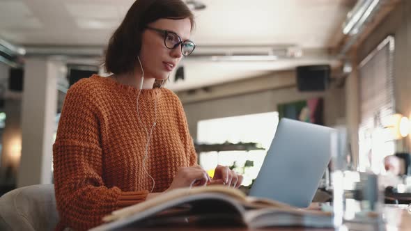 Meditative red haired woman texting by laptop