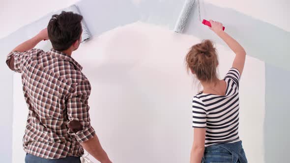 Young couple painting the interior wall in their new apartment 