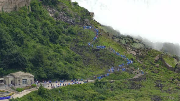 People in Blue Raincoat Climbing Stair Next to Niagara Falls, Establishing Shot