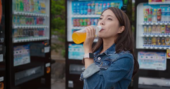 Woman drink of bottle of orange juice in vending machine