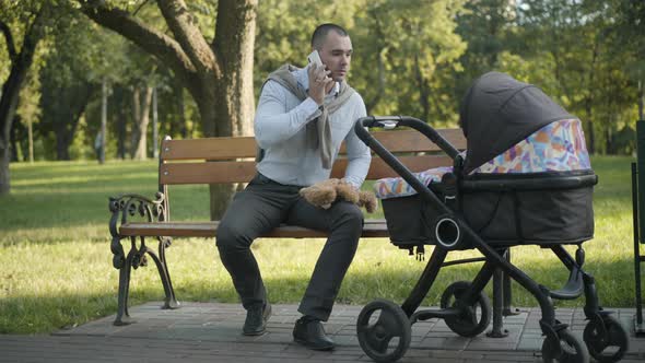 Wide Shot Portrait of Young Handsome Caucasian Man Talking on the Phone and Playing Teddy Bear with