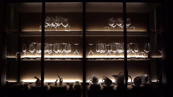 Black cupboard with glass wall in the kitchen with crockery and clear glasses.